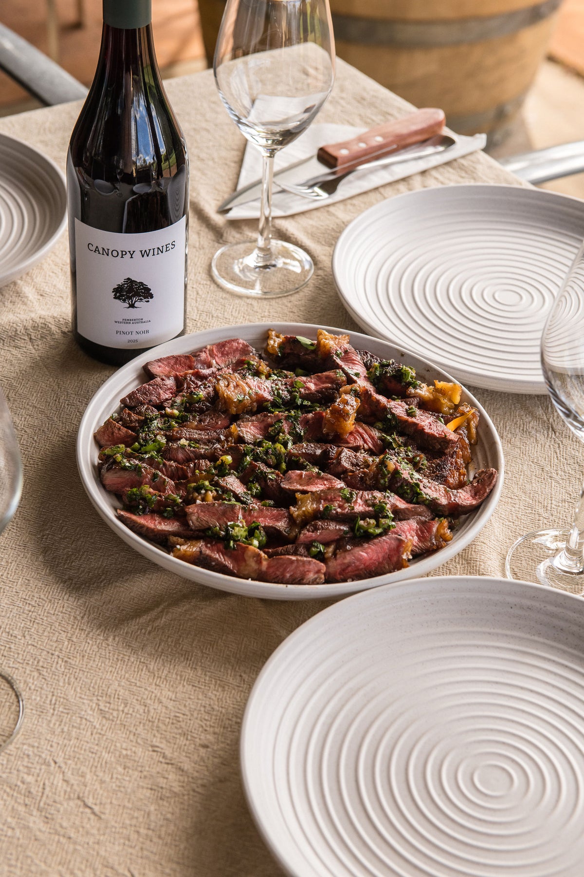 A bottle of Canopy Wines beside a platter of sliced grassfed beef on the long table