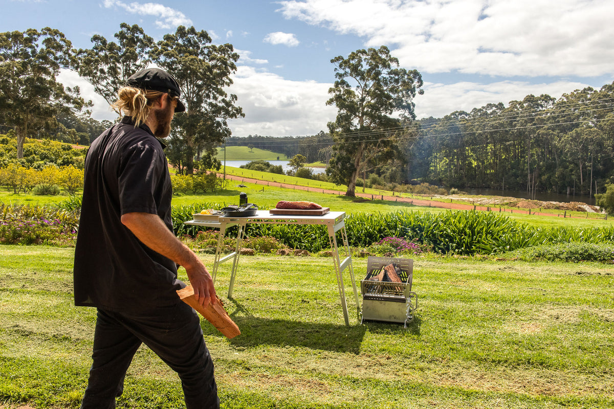 Glen walks past the outdoor fire kitchen set up on the farm lawn