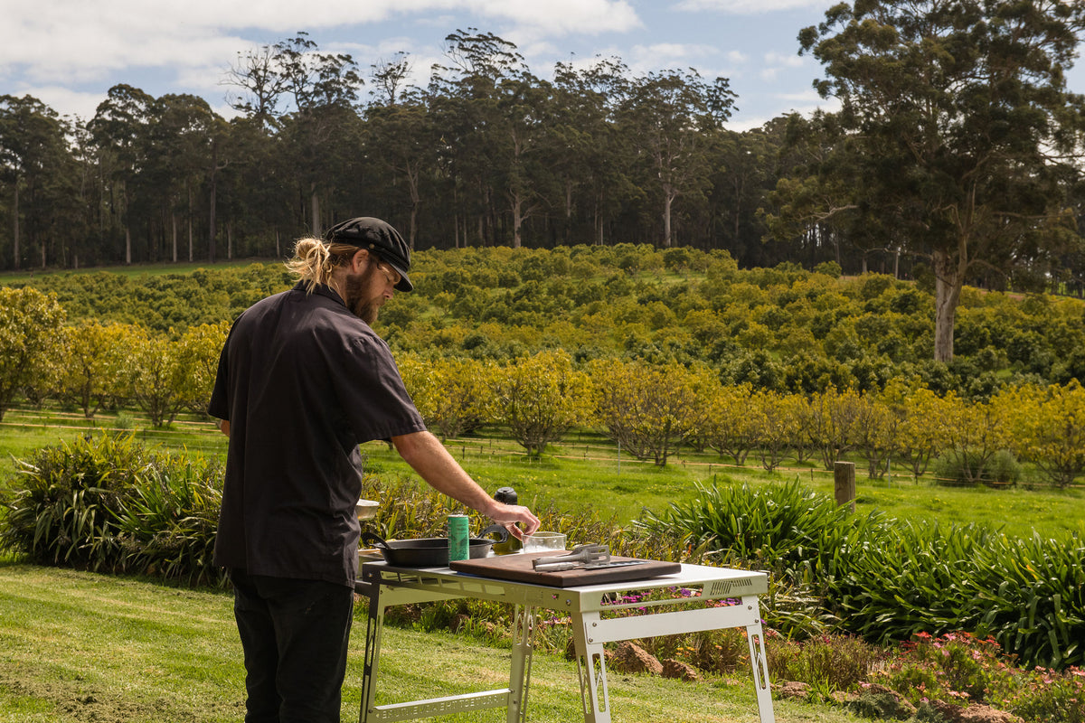 Glen at the Stratus Outdoors cooking table among the orchard trees