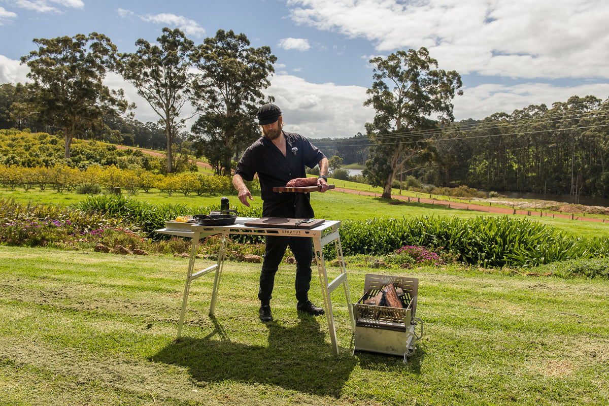 Glen cooks at a Stratus Outdoors grill table on the farm lawn
