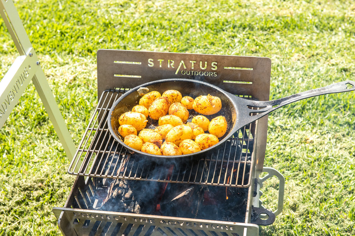 Potatoes roasting in a pan over a Stratus Outdoors fire grill